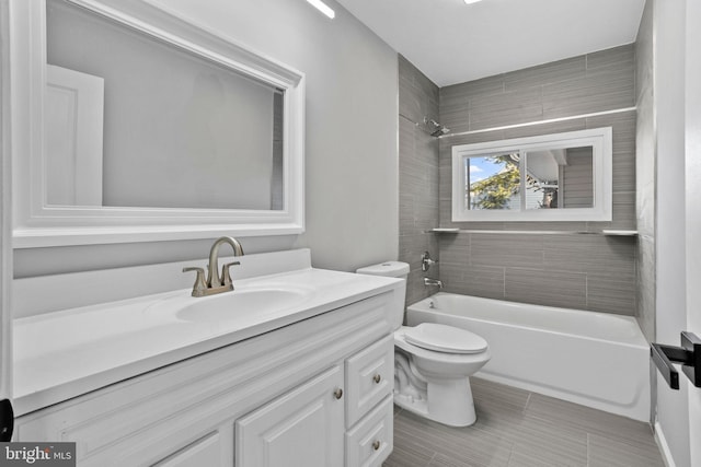 full bathroom featuring vanity, tiled shower / bath combo, and toilet