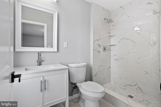 bathroom featuring a tile shower, vanity, and toilet