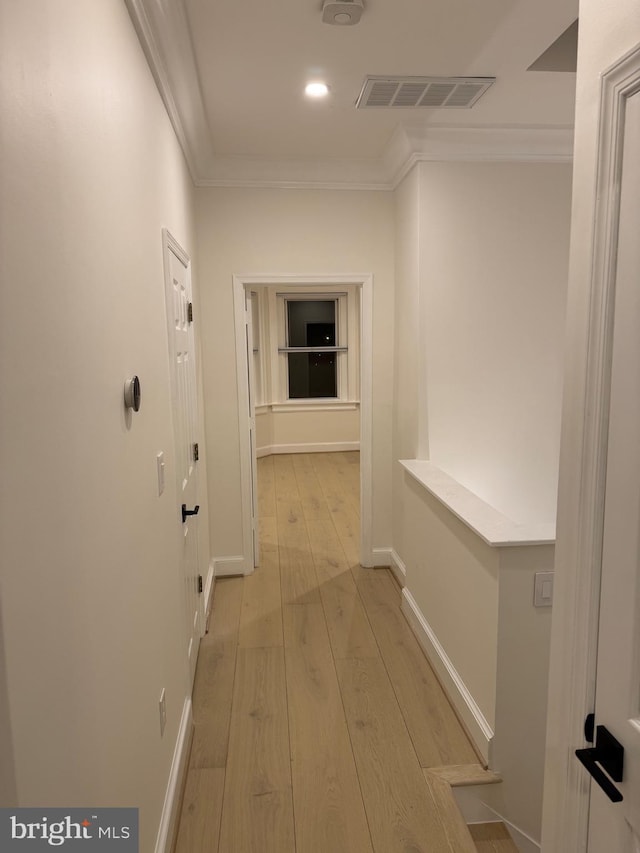 hallway featuring crown molding and light hardwood / wood-style flooring