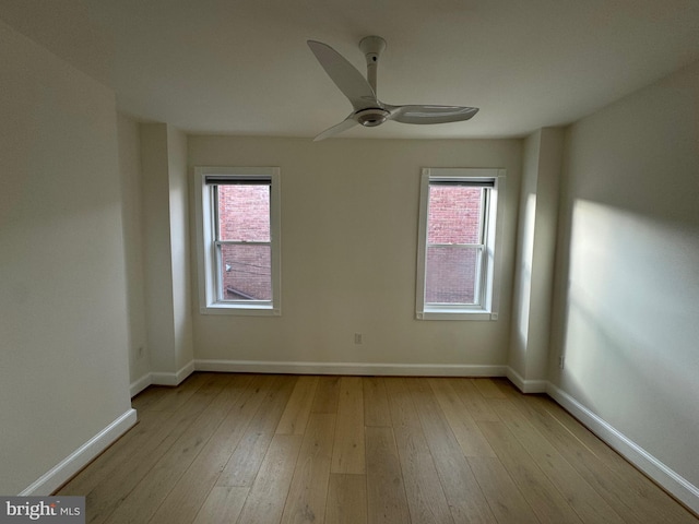 empty room featuring plenty of natural light, ceiling fan, and light wood-type flooring