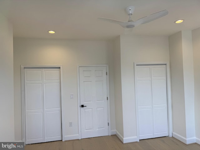 unfurnished bedroom featuring two closets, ceiling fan, and light hardwood / wood-style floors