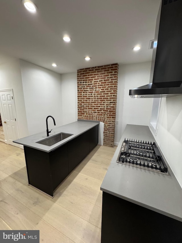 kitchen with light wood-type flooring, gas stovetop, range hood, and sink