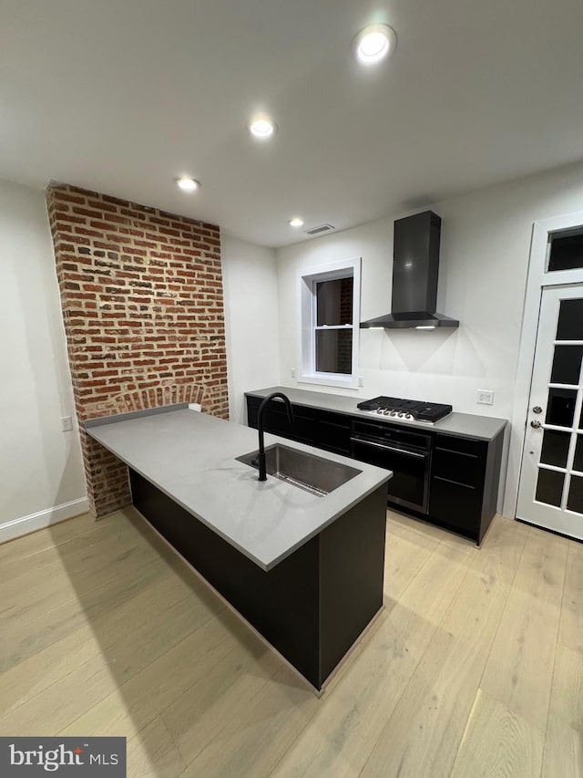 kitchen with sink, wall chimney range hood, brick wall, kitchen peninsula, and oven