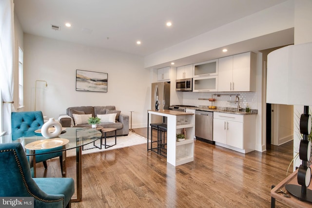 kitchen featuring a breakfast bar, stainless steel appliances, sink, light hardwood / wood-style flooring, and white cabinetry