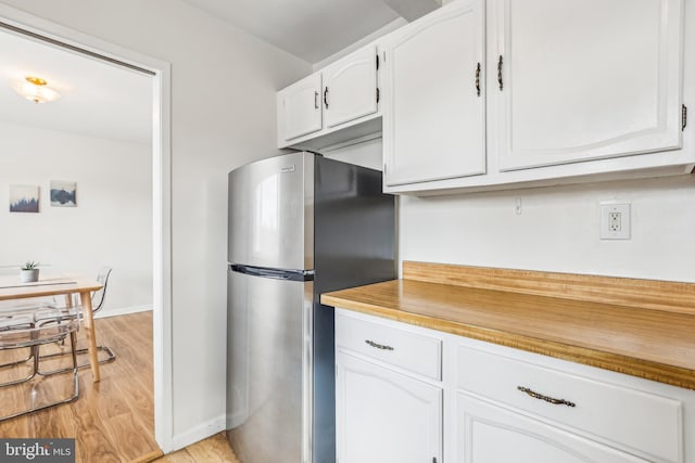 kitchen featuring white cabinets, stainless steel refrigerator, and light hardwood / wood-style flooring