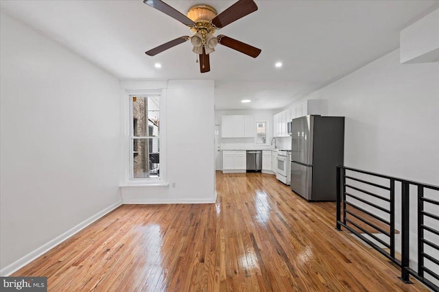 unfurnished living room with light hardwood / wood-style floors, ceiling fan, and sink