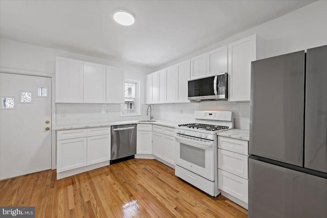 kitchen featuring white cabinets, sink, backsplash, and appliances with stainless steel finishes