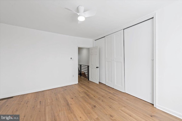 unfurnished bedroom featuring ceiling fan, light wood-type flooring, and a closet