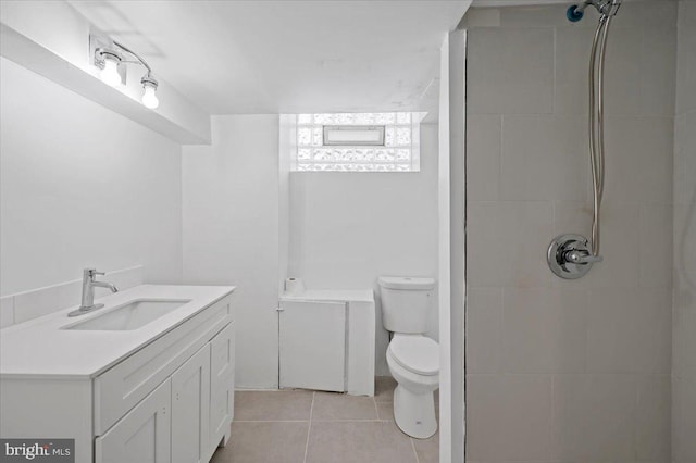 bathroom with tile patterned flooring, vanity, toilet, and tiled shower