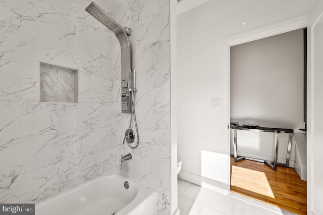 bathroom featuring tile patterned floors, toilet, and tiled shower / bath