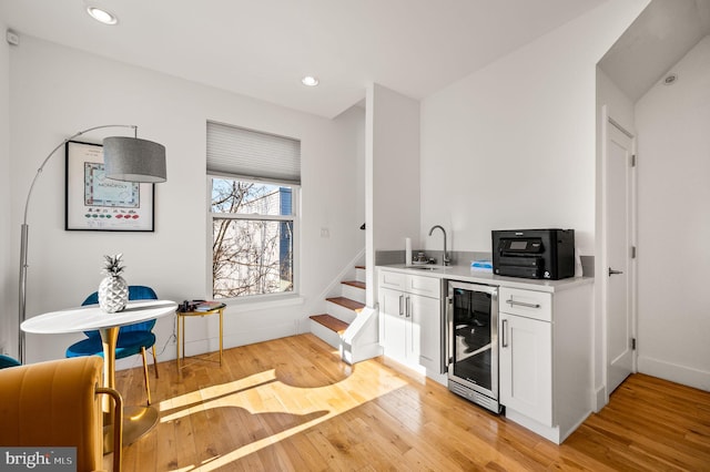 kitchen with light hardwood / wood-style flooring, white cabinets, beverage cooler, and sink