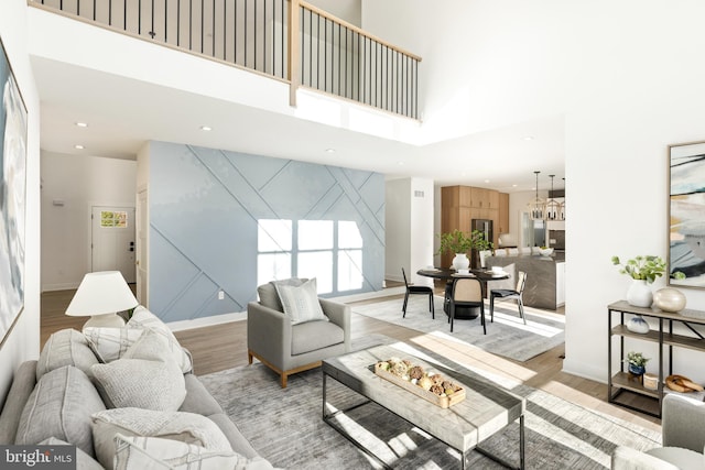 living room featuring light hardwood / wood-style flooring, a towering ceiling, and an inviting chandelier