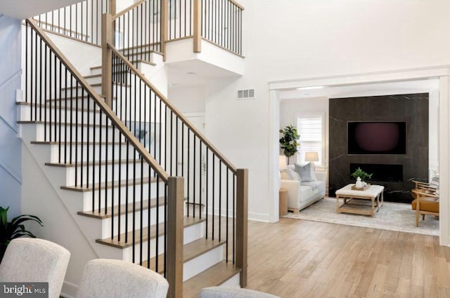 staircase with a large fireplace and hardwood / wood-style flooring