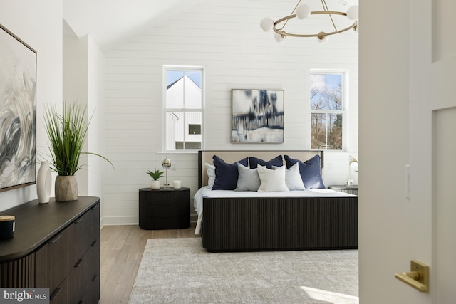 bedroom with a chandelier, light hardwood / wood-style floors, and vaulted ceiling