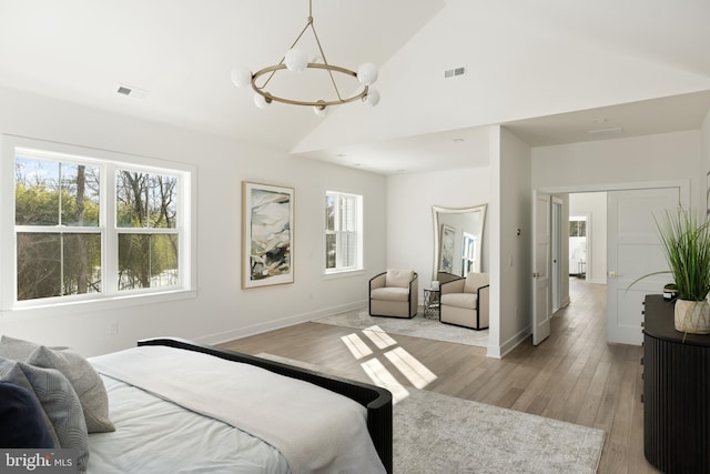 bedroom featuring vaulted ceiling, light wood-type flooring, and an inviting chandelier