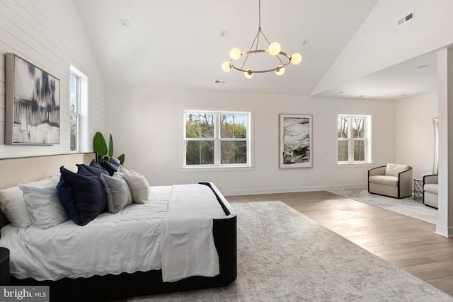 bedroom featuring hardwood / wood-style flooring, high vaulted ceiling, and an inviting chandelier