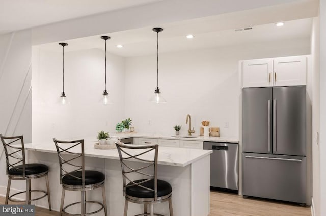 kitchen with white cabinets, decorative light fixtures, stainless steel appliances, and sink