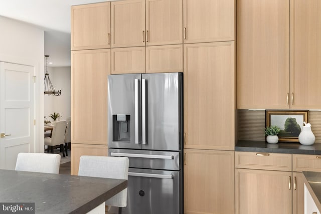 kitchen with stainless steel refrigerator with ice dispenser, decorative light fixtures, and light brown cabinetry