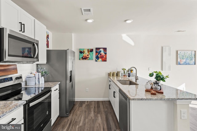 kitchen featuring white cabinets, sink, appliances with stainless steel finishes, light stone counters, and kitchen peninsula