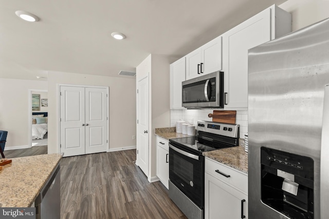 kitchen featuring light stone counters, dark hardwood / wood-style flooring, decorative backsplash, white cabinets, and appliances with stainless steel finishes