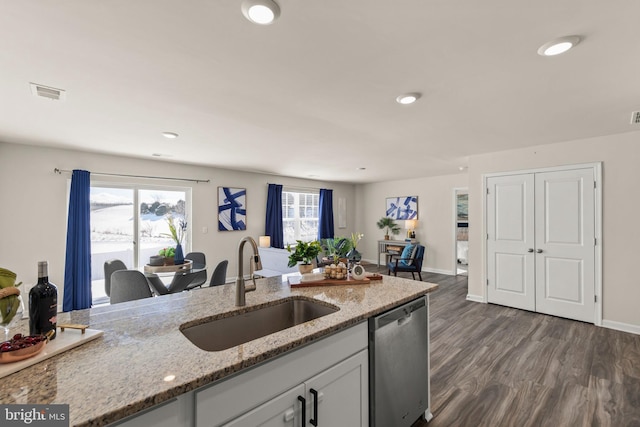 kitchen with stainless steel dishwasher, white cabinets, light stone counters, and sink