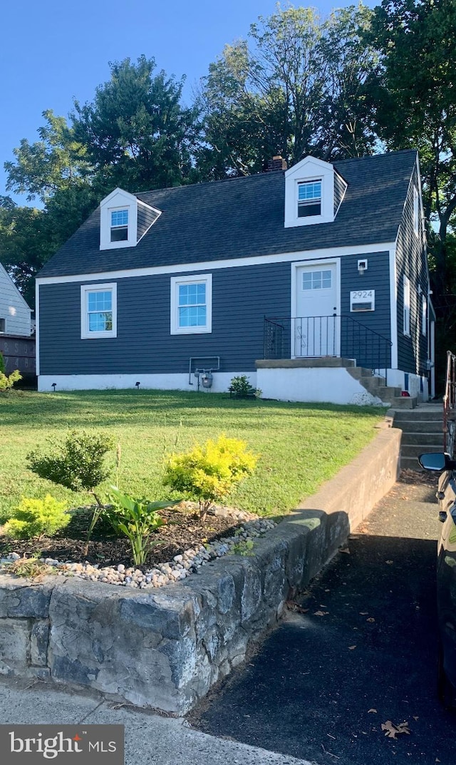 view of front facade featuring a shingled roof and a front lawn