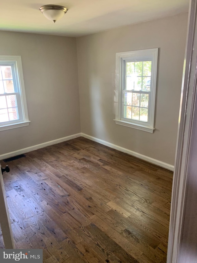 empty room with dark wood-style flooring and baseboards