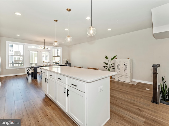 kitchen with pendant lighting, a center island, white cabinetry, and light hardwood / wood-style floors