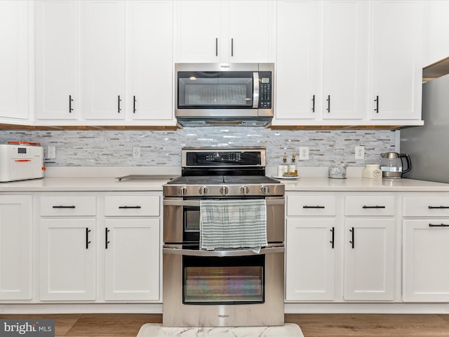 kitchen with white cabinets, decorative backsplash, and stainless steel appliances