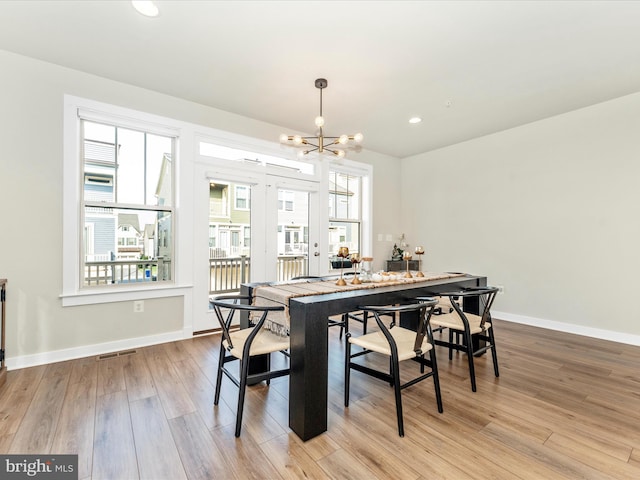 dining area with light hardwood / wood-style floors and a chandelier