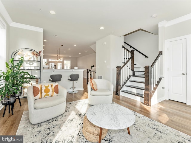 living room featuring crown molding, light hardwood / wood-style flooring, and an inviting chandelier