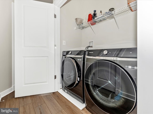 clothes washing area featuring hardwood / wood-style flooring and washer and clothes dryer