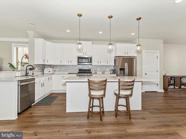 kitchen with a center island, sink, hanging light fixtures, appliances with stainless steel finishes, and white cabinetry