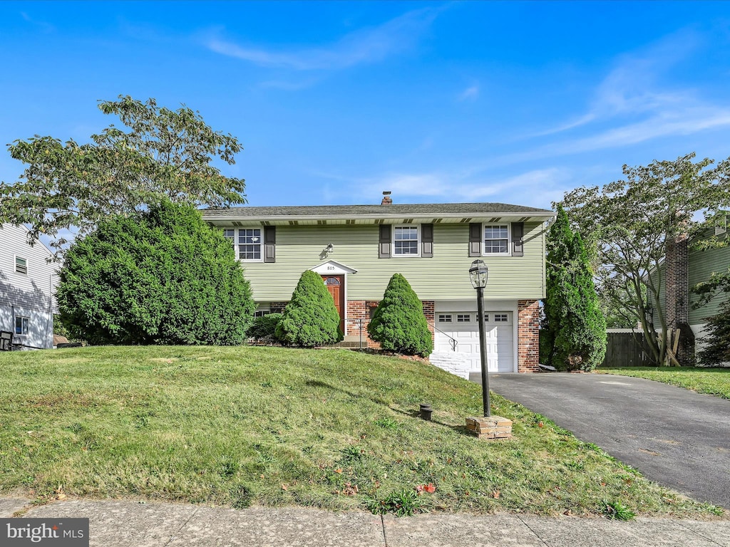 split foyer home with a garage and a front lawn