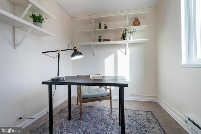 unfurnished office featuring carpet and a baseboard heating unit