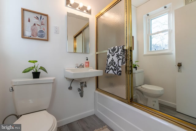 bathroom featuring wood-type flooring, bath / shower combo with glass door, and toilet