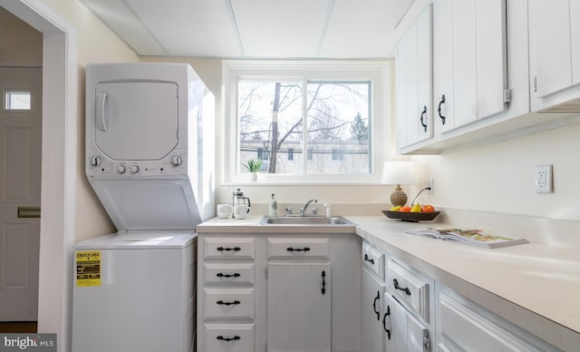 washroom with stacked washer and dryer, cabinets, and sink