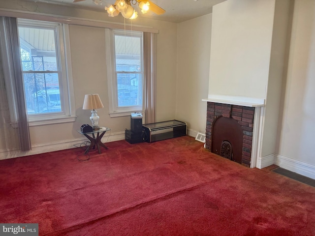 interior space featuring baseboards, a fireplace, a ceiling fan, and carpet flooring