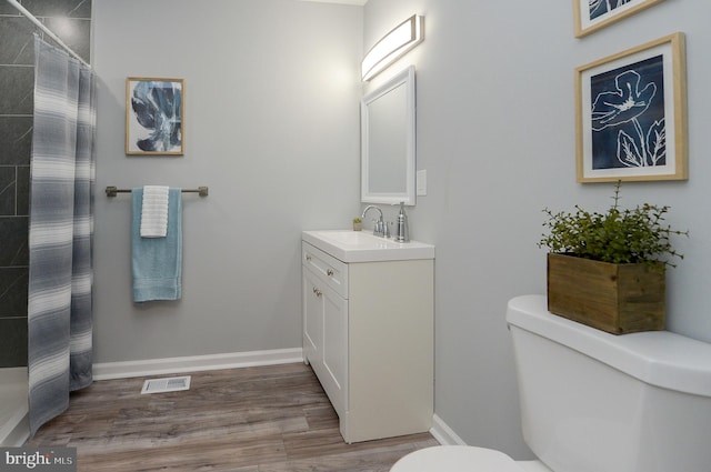 bathroom featuring hardwood / wood-style flooring, vanity, toilet, and walk in shower