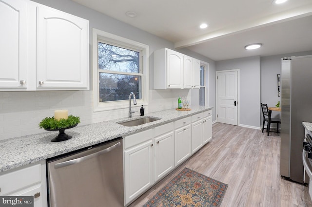 kitchen featuring light stone counters, stainless steel appliances, sink, light hardwood / wood-style flooring, and white cabinetry