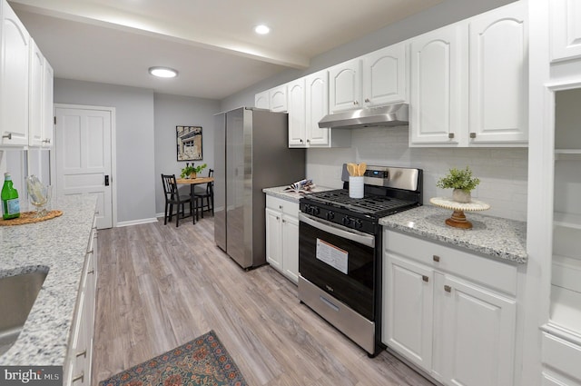 kitchen featuring decorative backsplash, light stone countertops, light wood-type flooring, stainless steel appliances, and white cabinets