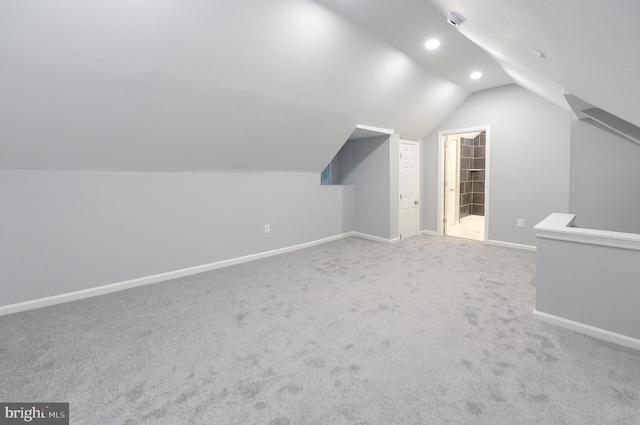 bonus room with light colored carpet and vaulted ceiling