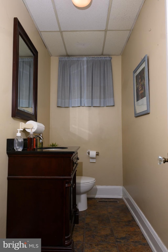 bathroom with a paneled ceiling, vanity, and toilet