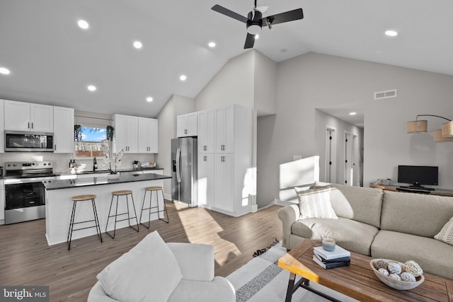 living room featuring ceiling fan, high vaulted ceiling, and light hardwood / wood-style floors