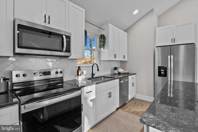 kitchen featuring lofted ceiling, sink, white cabinetry, and stainless steel appliances