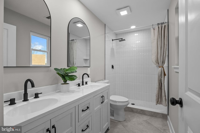 bathroom featuring tile patterned flooring, vanity, toilet, and a tile shower