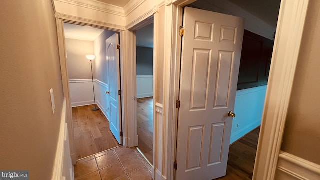 hallway with crown molding and tile patterned flooring