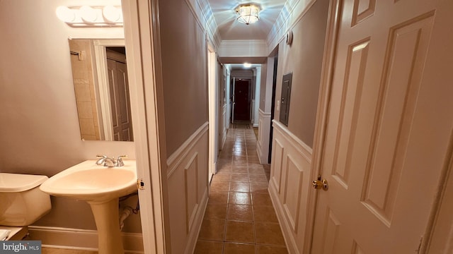 corridor with dark tile patterned flooring and ornamental molding