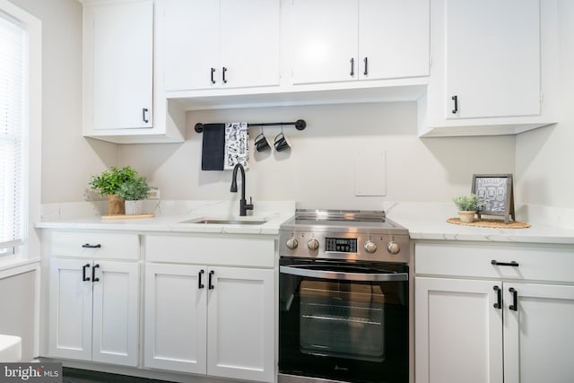 kitchen with sink, white cabinets, electric stove, and light stone counters