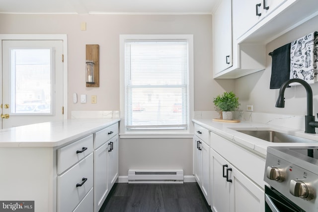 kitchen with baseboard heating, kitchen peninsula, white cabinets, stove, and sink